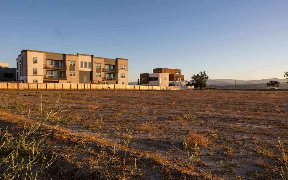 Empty plot beside a boundary wall and new apartment blocks